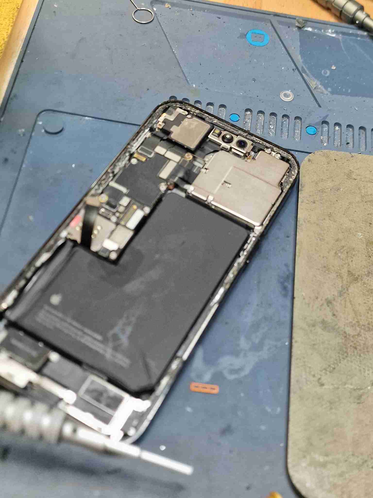 Reparação de iPhone 14 Pro Max danificado por água do mar, vista da placa lógica e bateria em oficina Reparação Mobile Portimão